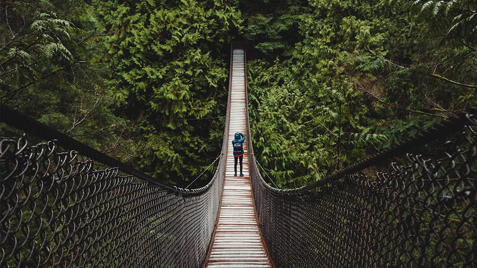 Diracs value: Courage. Man walking over a big hanging bridge.